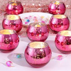 pink and gold glass candlesticks sitting on a table with confetti scattered around them