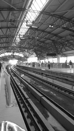 black and white photograph of people waiting at the train station for their trains to arrive