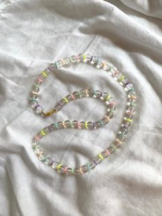 a beaded necklace is laying on top of a white sheet with a gold clasp