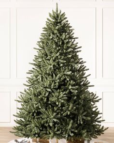 a small christmas tree sitting on top of a glass table next to a white wall