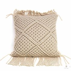 a crocheted pillow with tassels on it