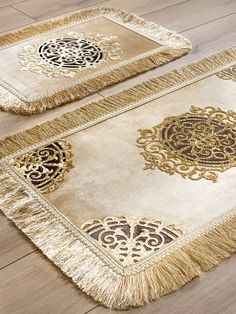 two gold rugs with black and white designs on them sitting on a wooden floor