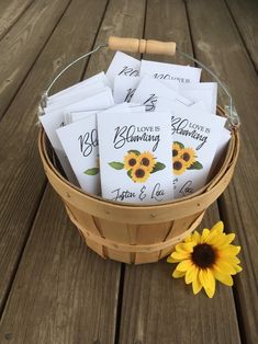 a basket filled with lots of cards sitting on top of a wooden table next to a sunflower