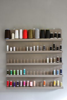 a wall shelf filled with lots of spools of thread