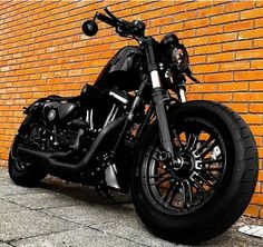 a black motorcycle parked in front of a brick wall