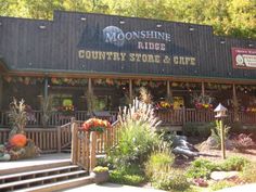 the front of a country store and cafe with flowers in pots on the steps outside