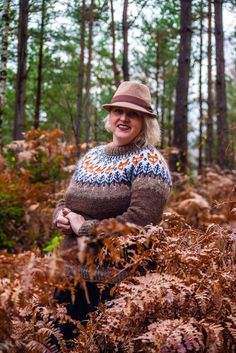 a woman wearing a hat and sweater in the woods