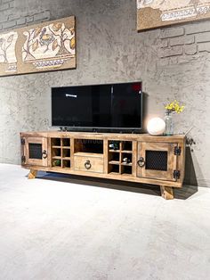 an entertainment center with two large televisions on top of it, in front of a brick wall