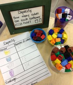 a wooden table topped with cups filled with legos and paper on top of it