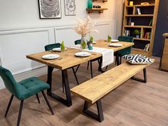 a wooden table with green chairs and plates on it