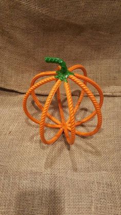 an orange plastic pumpkin sitting on top of a brown cloth covered couch next to a pillow