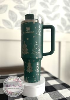 a green travel mug sitting on top of a white and black checkered tablecloth