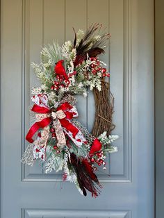 a wreath with red and white ribbons hanging on a door