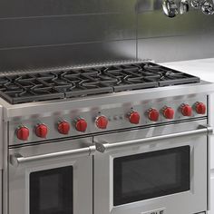 a stainless steel stove with red knobs and two burners on the front side