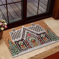 a door mat with a christmas scene on it next to a vase filled with flowers