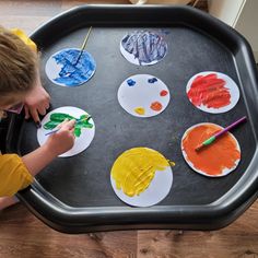 a young boy painting on paper plates with paint