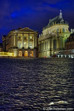 an old building is lit up at night in the middle of a cobblestone street