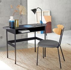 a desk with a chair, lamp and books on it