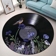 a blue couch sitting next to a black record on top of a floor covered in flowers