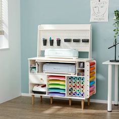 a white desk with lots of crafting supplies on it and a blue wall in the background