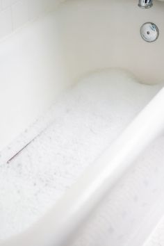 a white bath tub filled with water next to a faucet