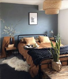 a bed room with a neatly made bed and a plant on the end of it