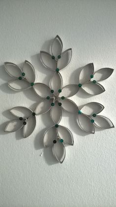 a metal snowflake with green beads hanging from it's side on a wall