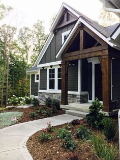 a house that is in the middle of some plants and flowers on the front lawn