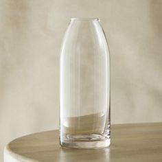 a clear glass vase sitting on top of a wooden table next to a white wall