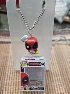 the deadpool keychain is on display in a plastic container with a chain attached to it