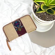 a small purse sitting on top of a white table next to a potted plant