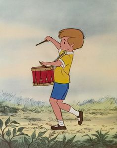 a boy holding a drum in his hand and pointing to something on the other side