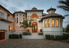 a large white house with lots of windows on the front and side of it at dusk