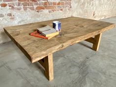 a wooden table with two books and a cup on it next to a brick wall