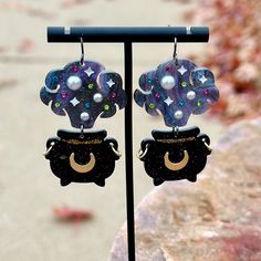 the earrings are decorated with stars and moon designs on black acrylic material, along with pearl beads