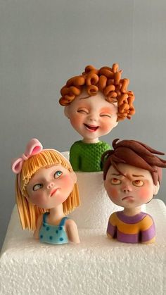 three small figurines sitting on top of a cake