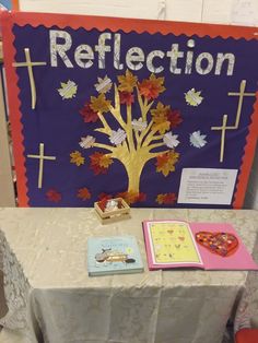 a table topped with books and a sign that says reflection next to it is a tree