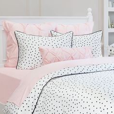 a white and pink bed with polka dots on the comforter, pillows and pillow cases