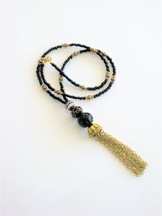 Bohemian Style black and gold beaded necklaces, handmade by Ralston Originals. These beautiful tassel necklaces come in your choice of 3 different Styles. I made the tassels with gold metal chain, and a large antique gold cap. I made the first necklace (pictures 1-3), with a large black bead with gold metal dots, and a black bead with gold stripes. The beaded chain is made with black seed beads, and gold acrylic beads. This necklace is 28 inches long, and has a lobster clasp. I made the second n Adjustable Elegant Tassel Necklace For Festival, Adjustable Long Tassel Necklace With Dangling Beads, Gold Beaded Dangle Tassel Necklace, Lariat Beaded Necklace With Tassels For Gift, Gift Lariat Beaded Necklace With Tassels, Elegant Long Necklace With Beaded Chain For Festivals, Elegant Long Beaded Chain Necklace For Festivals, Adjustable Tassel Necklace With Dangling Beads As Gift, Adjustable Tassel Necklace With Dangling Beads For Gift