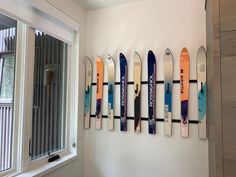 a row of skis mounted to the side of a wall next to a window