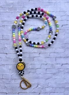 a multicolored beaded lanyard with a smiley face charm hanging from it