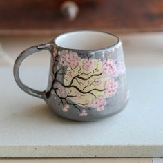 a coffee cup with pink flowers painted on the inside and outside, sitting on a counter