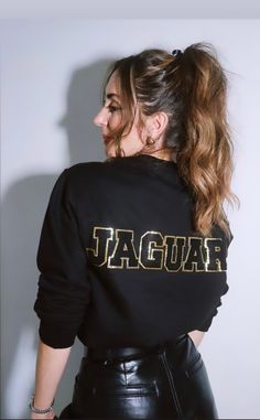 a woman wearing a black sweatshirt with the word jaguar printed on it, and her hair in a pony tail