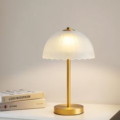 a lamp sitting on top of a white table next to a book and a remote control