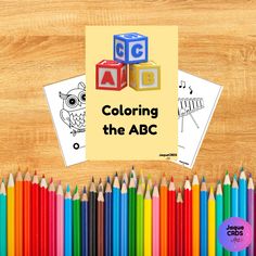 coloring the abc with colored pencils and paper on wooden table next to colorful crayons