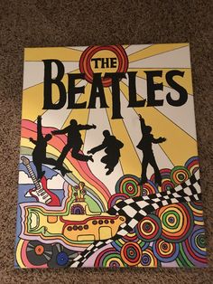 the beatles poster is laying on the floor in front of a carpeted flooring area