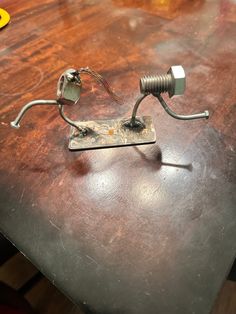 a metal object sitting on top of a wooden table next to a light bulb and some wires