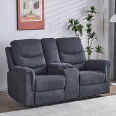 the reclining loveseat has two seats and is next to a potted plant