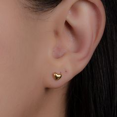 a close up of a person's ear with gold heart studs on it