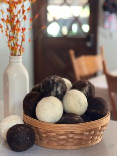 a basket filled with brown and white donuts on top of a table next to a vase